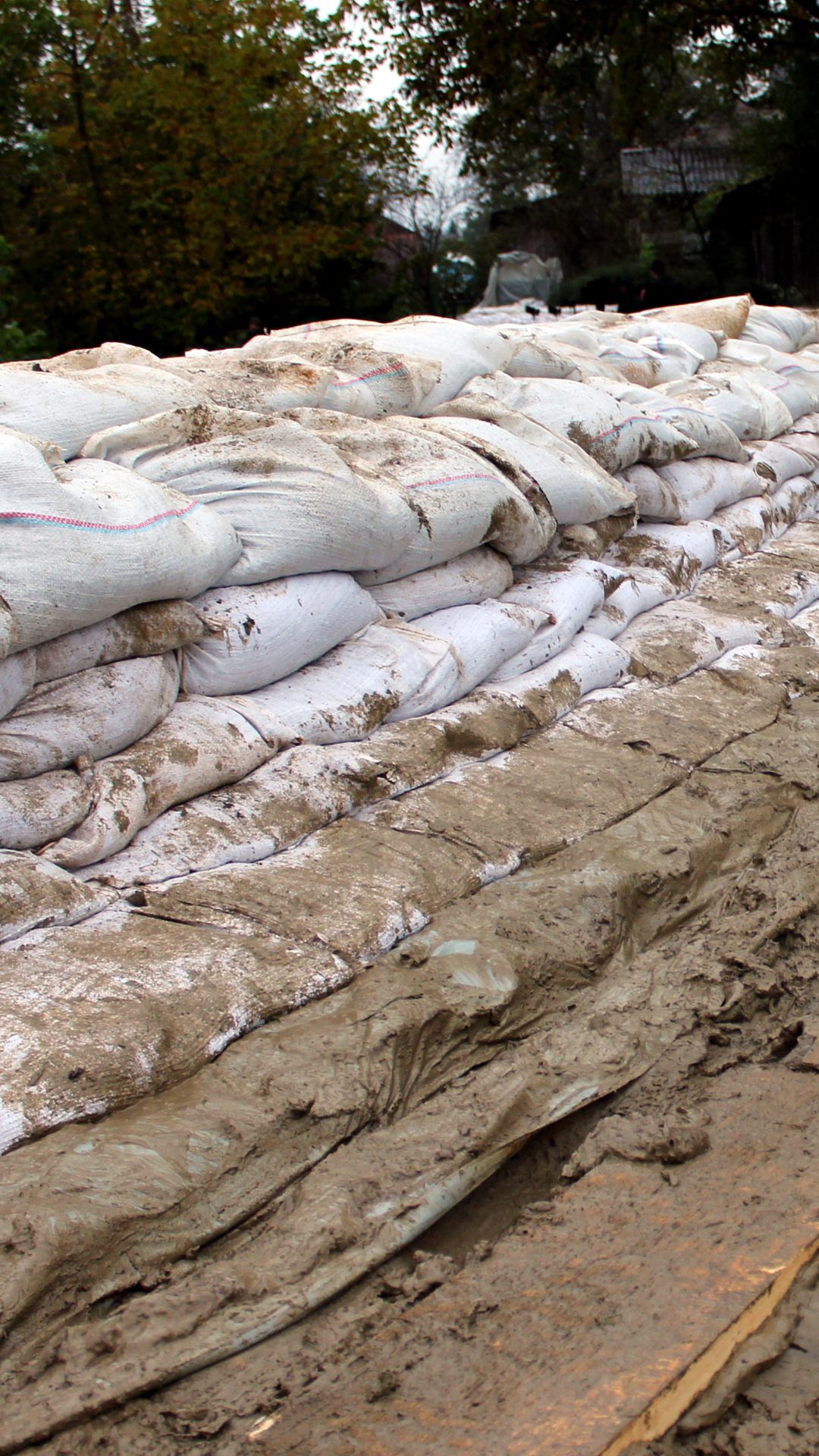 Sandbags are stacked in multiple rows and covered with mud on the bottom rows.